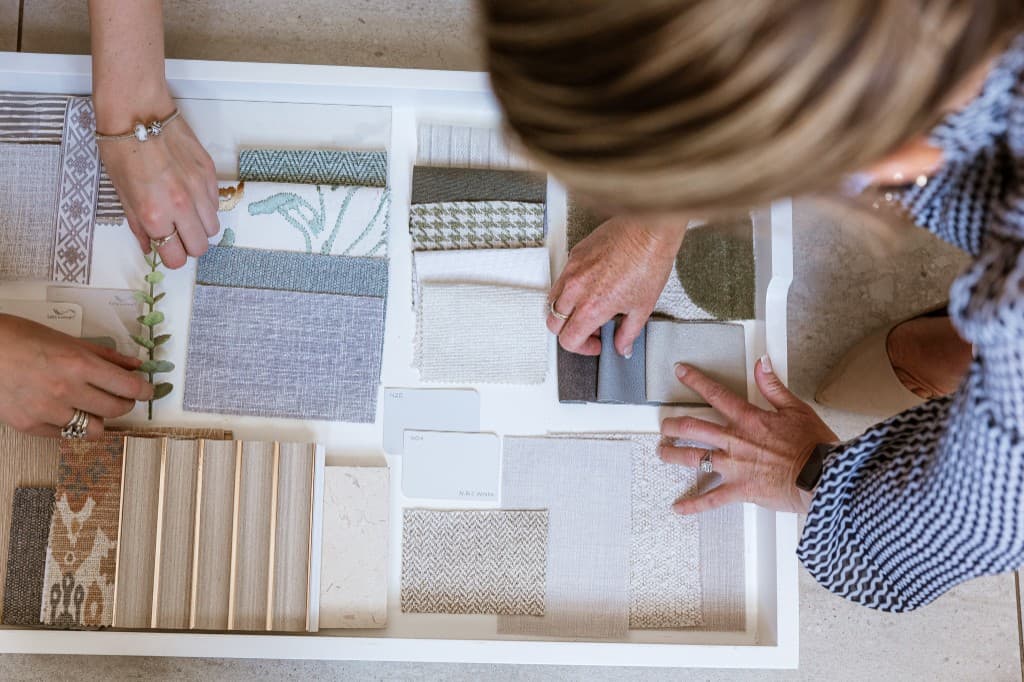 Designers arranging fabric and finish samples on a tray during a consultation.