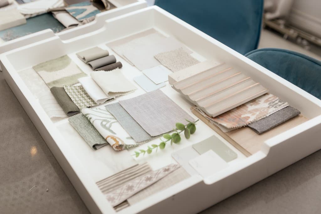 Overhead view of layered fabric and finish samples with natural greenery.