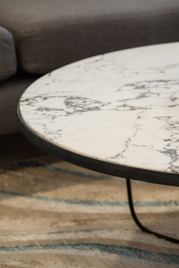 Round white marble coffee table with dark metal frame on a patterned area rug