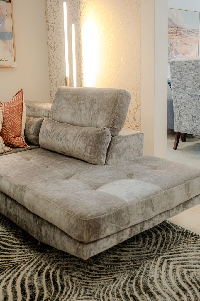 Taupe chaise sectional with metallic branch wallpaper and vertical accent lighting