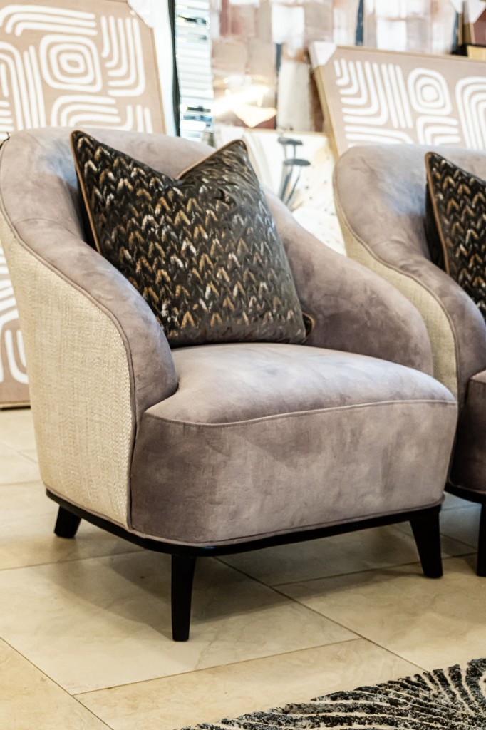 Mauve club chair with patterned throw pillow in a curated showroom setting