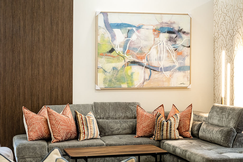 Charcoal velvet sectional with abstract wall art and warm wood feature wall