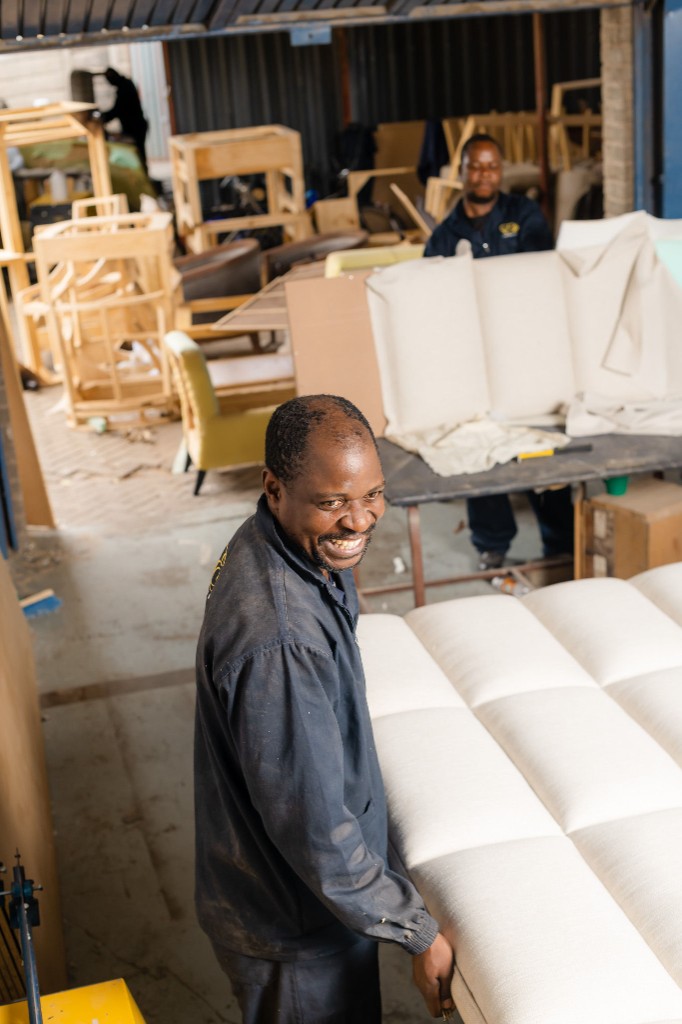 Craftsperson hand-finishing tufted upholstery in the workshop.